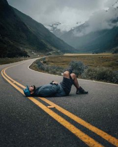 A guy lies in the middle of a road.